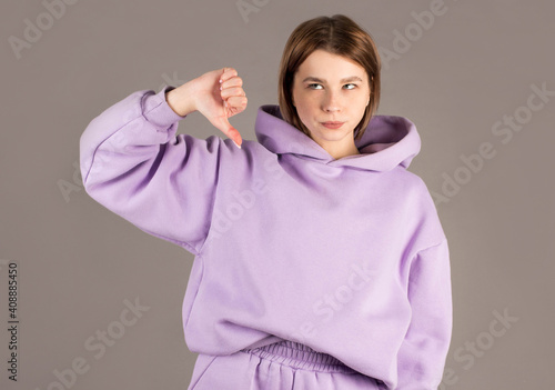 Woman showing thumbs down isolated on gray background