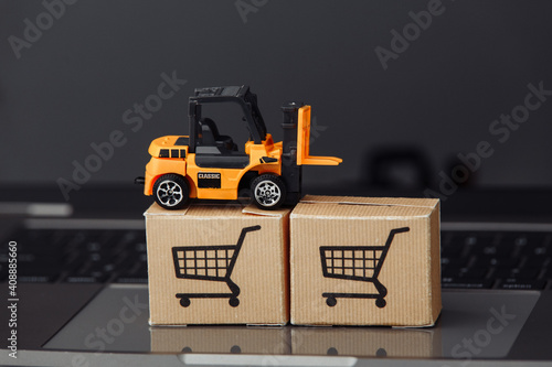 Forklift model on carton boxes on a laptop. Courier services and delivery concept.