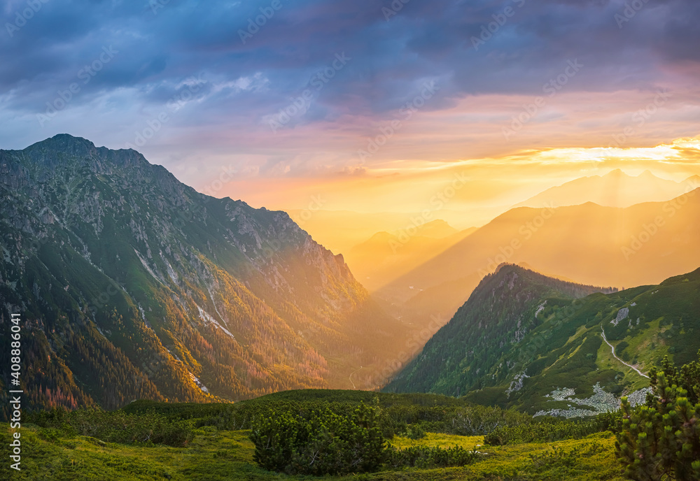 Golden sunset with sunbeams in big mountain landscape