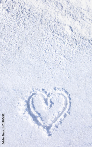 Hand drawn of a heart shape on natural pure bright white soft snow surface in cold weather in the winter season, a symbol of love. A romantic idea for Valentine's day. Vertical banner with copy space. photo