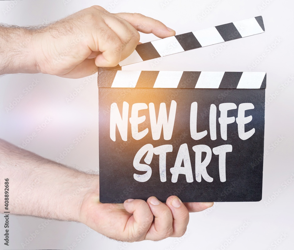 On a white background, a man holds a clapperboard in his hands on which it is written - NEW LIFE START