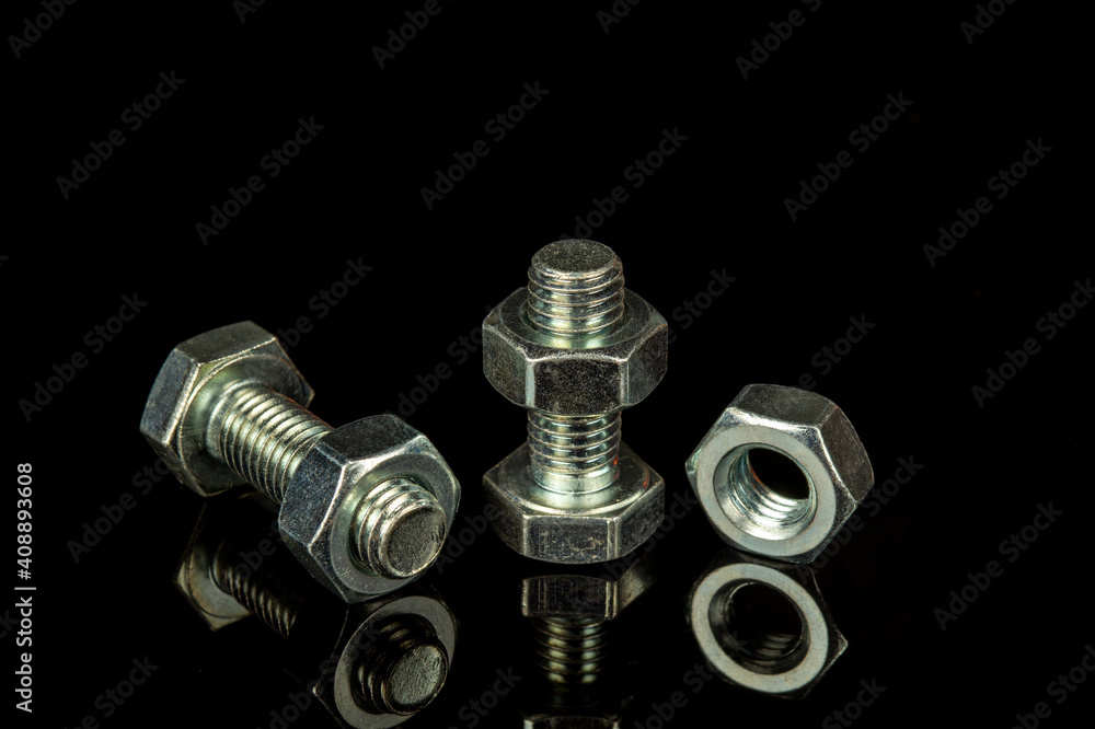 Metal bolts and nuts on a black isolated background is used in construction to connect parts Metal bolts and nuts on a black isolated background is used in construction to connect parts