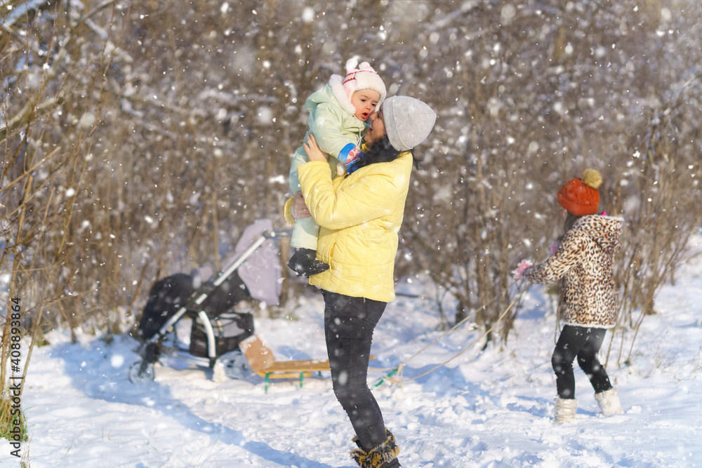 Fototapeta premium family walks in the winter forest, mother and children, bright sunlight and shadows on the snow, beautiful nature