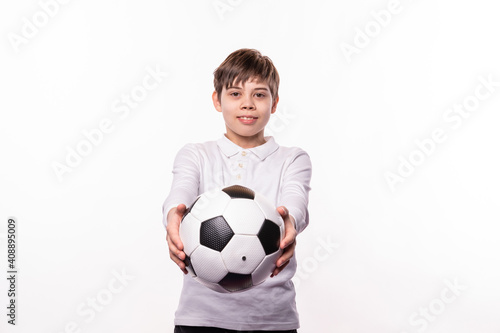 A happy young boy holding a soccer ball is looking and smiling at the camera © Sergiu