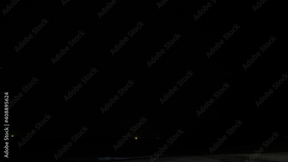 Dark cloudy sky over sea, bright flashes of thunderstorm lightning and illuminate heavy clouds around. Time lapse shot. Small lights of fishing boats seen on waver