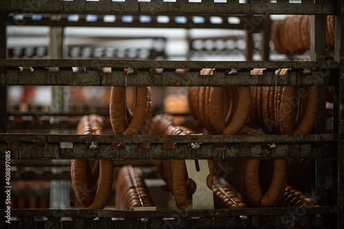 Fresh sausages hang on hangers in the production hall. Meat industry.