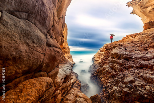 Long exposure landscape of the cave, sea and a woman with umbrella in Akyar, Silifke, Mersin, Turkey. photo