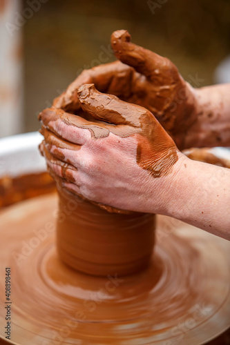A potter makes dishes out of brown clay. Dirty worker s hands close up.