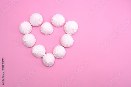 The heart is lined with small marshmallows on a pink background. Background for valentine's day.