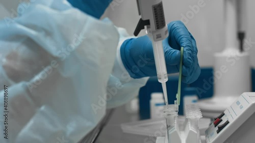 Process of studying dangerous bacteria and viruses in high tech medical laboratory. Scientist in protective suit and gloves examines biological samples in test tubes photo