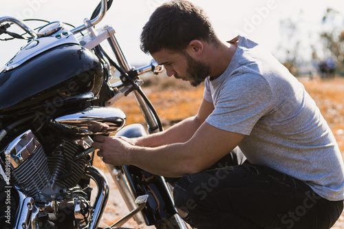 Crouching biker worried about a motorcycle breakdown