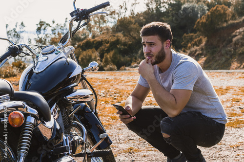 Crouching biker worried about a motorcycle breakdown