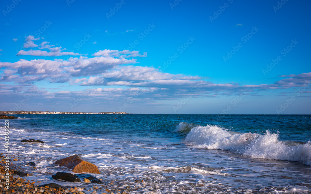 Seascape with white waves and clouds over the rocky windy beach