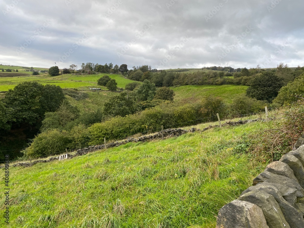 View of the countryside, from a dry stone wall, with sloping fields, valleys, and hills near, Ripponden, Lancashire, UK