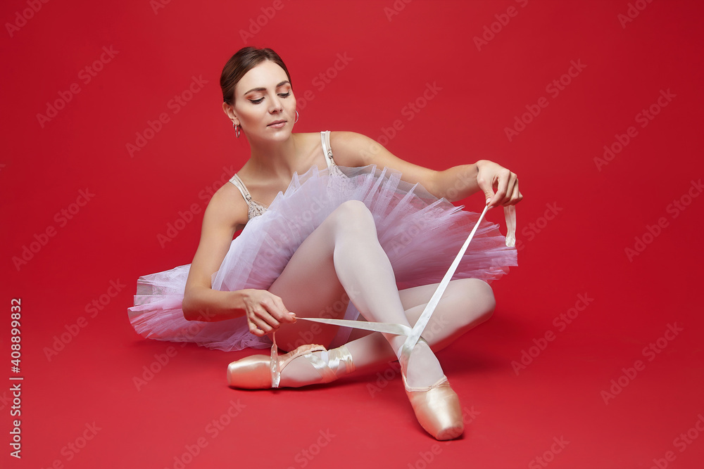 attractive ballerina poses in the studio on a red background attractive ballerina poses in the studio on a red background