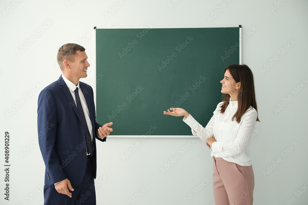 Man and woman talking near green chalkboard in classroom Man and woman talking near green chalkboard in classroom