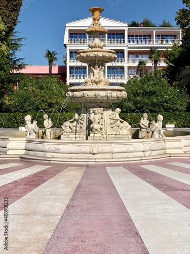 White fountain with statues in the center of the park.