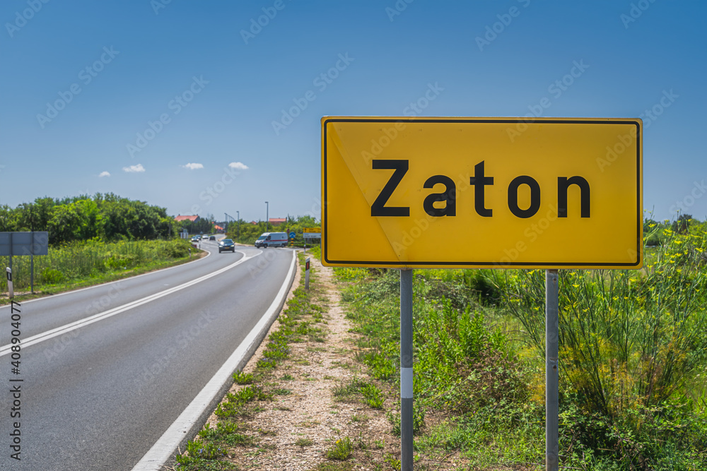 Large yellow, Zaton city welcome sign with cars on a road and green field on roadside, Croatia Large yellow, Zaton city welcome sign with cars on a road and green field on roadside, Croatia
