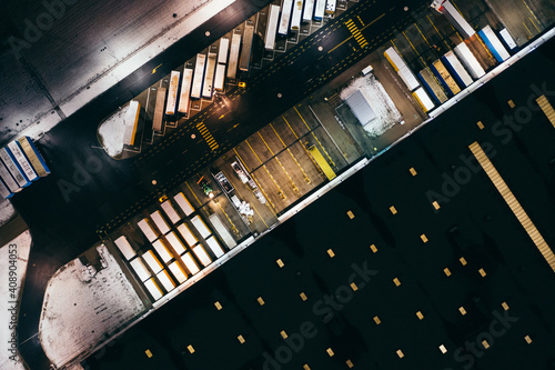 Aerial view of the trucks unloading at the logistic center. Night view with a bit of snow.