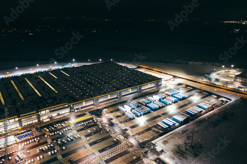 Aerial view of the trucks unloading at the logistic center. Night view with a bit of snow.