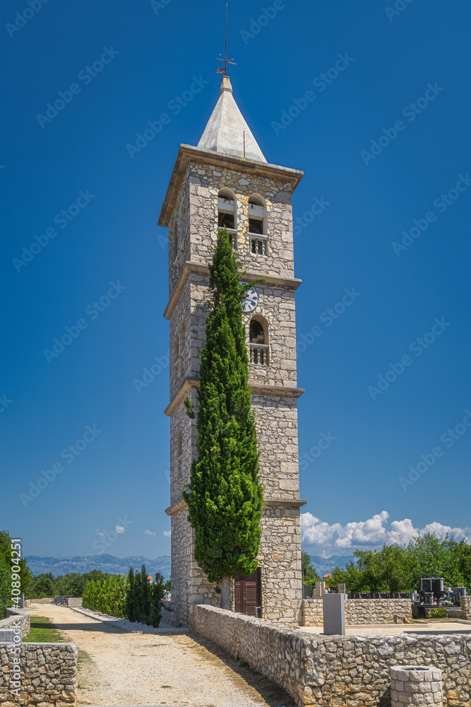 Bell and clock tower of a Church of the Nativity of the Blessed Virgin Mary in Zaton with Dinaric Alps in a background, Croatia