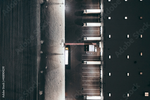 Aerial view of the trucks unloading at the logistic center. Night view with a bit of snow.