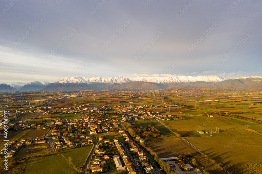 small villages and fields against the backdrop of beautiful snowy mountains, view from a drone