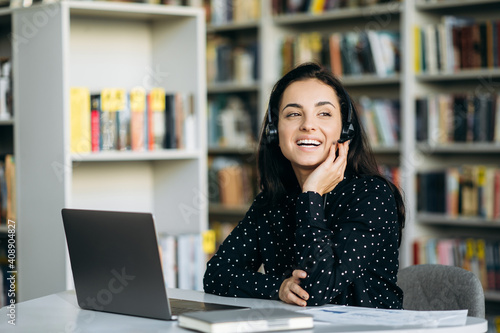 Pretty woman, consultant in headset talking with clients. Joyful female caucasian lady work as operator of call center, support service concept