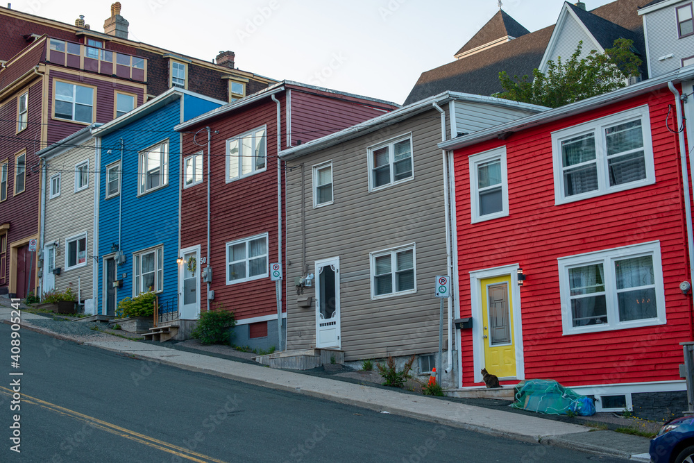 St. John's, NL Canada-January 2021:A row of colourful wooden houses on a small narrow street in St. John's, Newfoundland with sidewalks and pavement exposed on a steep hill. St. John's, NL Canada-January 2021:A row of colourful wooden houses on a small narrow street in St. John's, Newfoundland with sidewalks and pavement exposed on a steep hill.