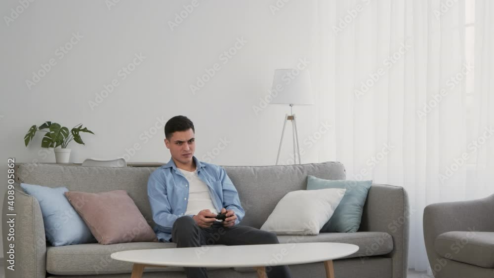 Young man playing video games with joystick, losing and feeling irritated, slow motion Young man playing video games with joystick, losing and feeling irritated, slow motion