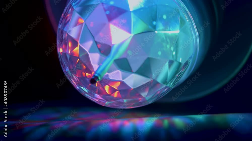 A spinning small disco ball on the ceiling giving lights inside the dark room A spinning small disco ball on the ceiling giving lights inside the dark room