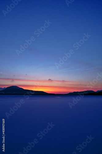 Fototapeta Naklejka Na Ścianę i Meble -  氷った真冬の湖の夜明け。薄明の下の結氷した湖。日の出前の空のグラデーション。屈斜路湖、北海道、日本。