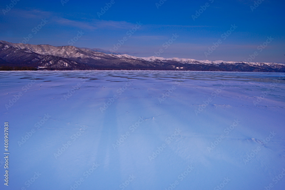 氷に覆われた冬の湖の朝の風景。日本の北海道の屈斜路湖で。