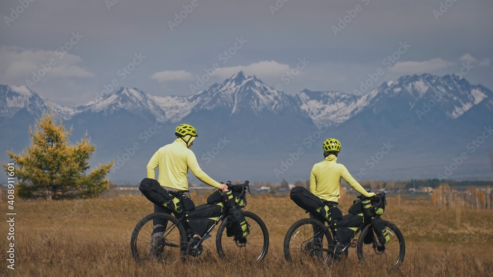 The man and woman travel on mixed terrain cycle touring with bikepacking. The love couple journey with tent in nature with bicycle bags. Stylish bikepacking, bike, sportswear in green black colors.