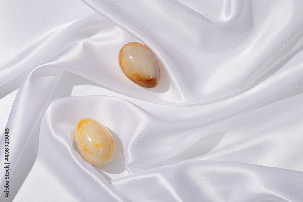 Easter eggs made from Natural gemstone onyx on white cloth texture background. Trendy spring holiday arrangement. Easter eggs made from Natural gemstone onyx on white cloth texture background. Trendy spring holiday arrangement.