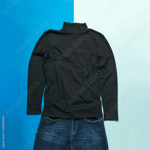 Black men's sweater and jeans on a two-tone background.