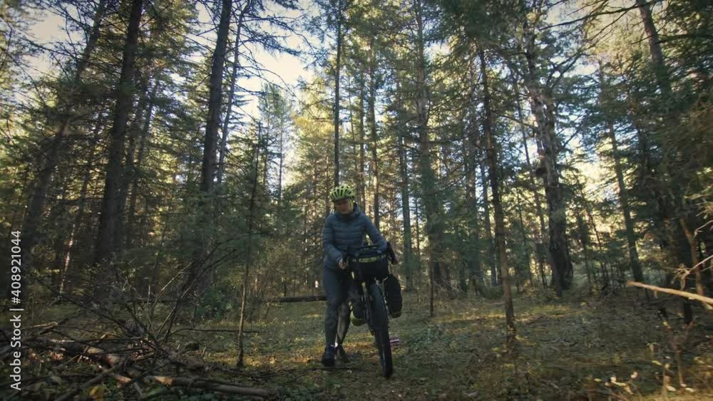 The woman travel on mixed terrain cycle touring with bike bikepacking outdoor. The traveler journey with bicycle bags. Stylish bikepacking, bike, sportswear in green black colors. Magic forest park. The woman travel on mixed terrain cycle touring with bike bikepacking outdoor. The traveler journey with bicycle bags. Stylish bikepacking, bike, sportswear in green black colors. Magic forest park.