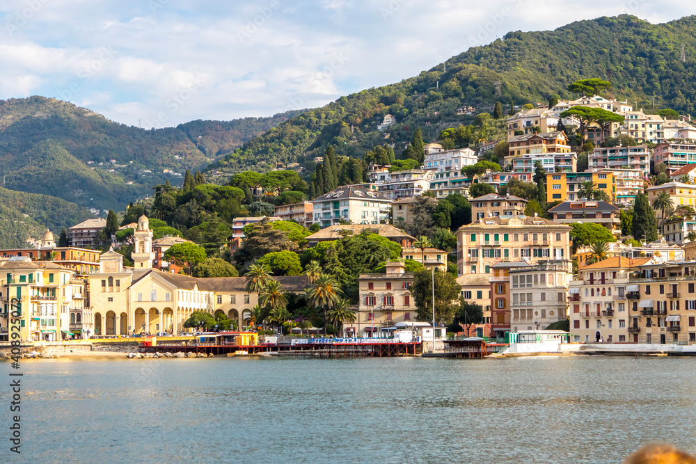 Italy. A picturesque town on the Ligurian coast. Colorful colorful Mediterranean houses on the coastline of a stone beach among green trees. A popular resort and tourist destination.
