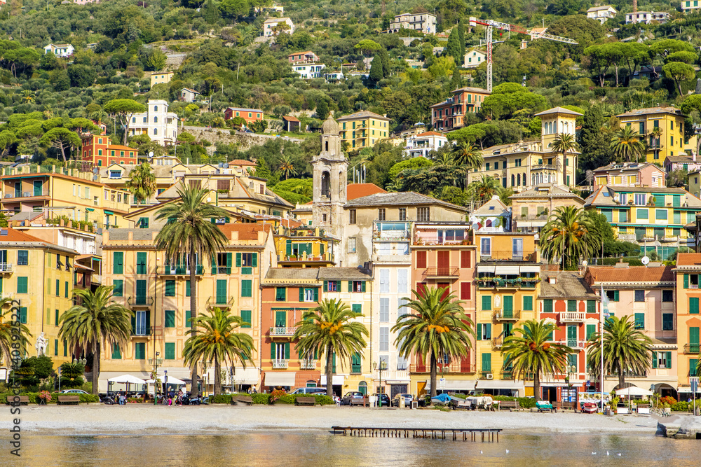 Italy. A picturesque town on the Ligurian coast. Colorful colorful Mediterranean houses on the coastline of a stone beach among green trees. A popular resort and tourist destination.