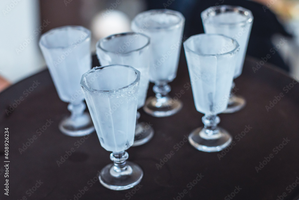 View of alcohol setting on catering banquet table, row line of ice cold vodka shots decorated catering bouquet table event View of alcohol setting on catering banquet table, row line of ice cold vodka shots decorated catering bouquet table event