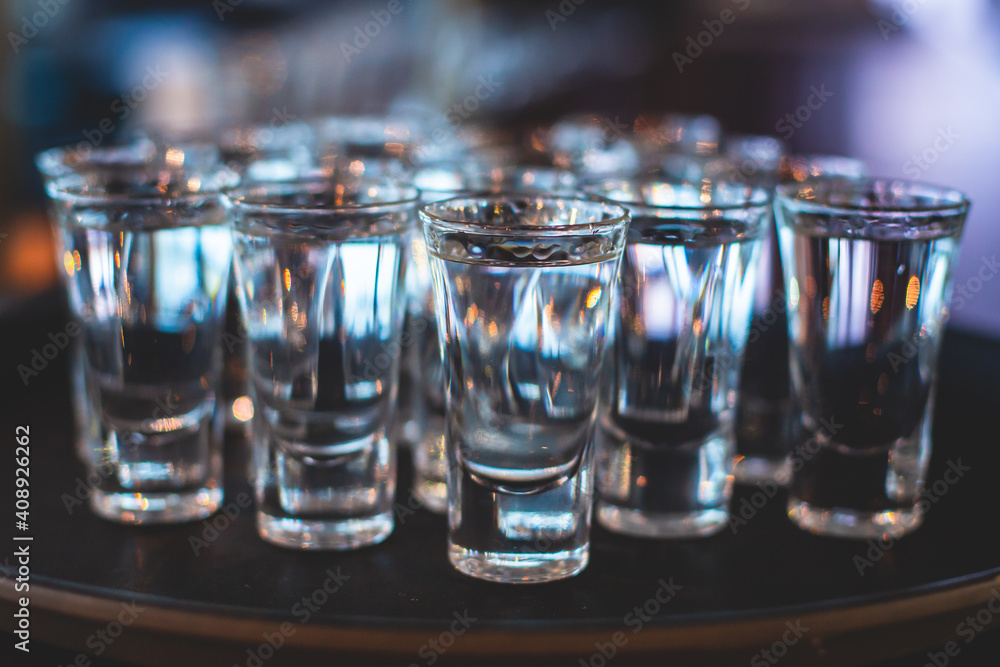 View of alcohol setting on catering banquet table, row line of ice cold vodka shots decorated catering bouquet table event View of alcohol setting on catering banquet table, row line of ice cold vodka shots decorated catering bouquet table event
