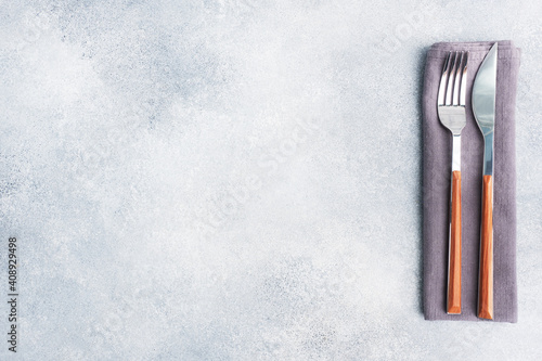 Cutlery knife and fork on a napkin  gray concrete background  copy space top view.