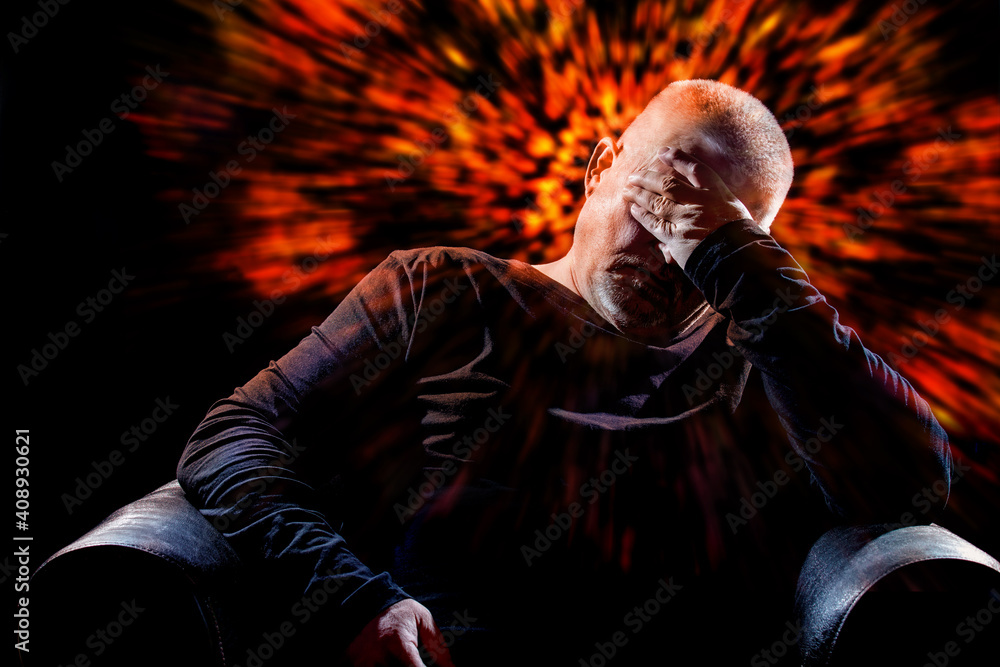 A man with a severe headache is sitting in an armchair. His head is surrounded by lights.