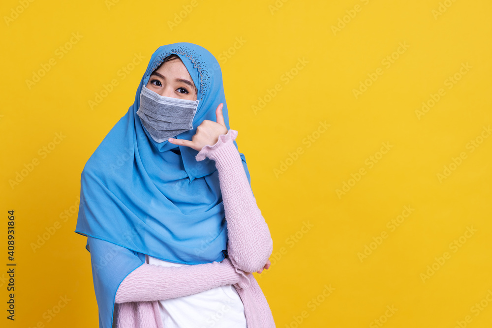 Asian muslim woman in medical mask to protect Coronavirus COVID-19 pandemic disease and showing make the calling sign by her left hand. Asian muslim woman in medical mask to protect Coronavirus COVID-19 pandemic disease and showing make the calling sign by her left hand.