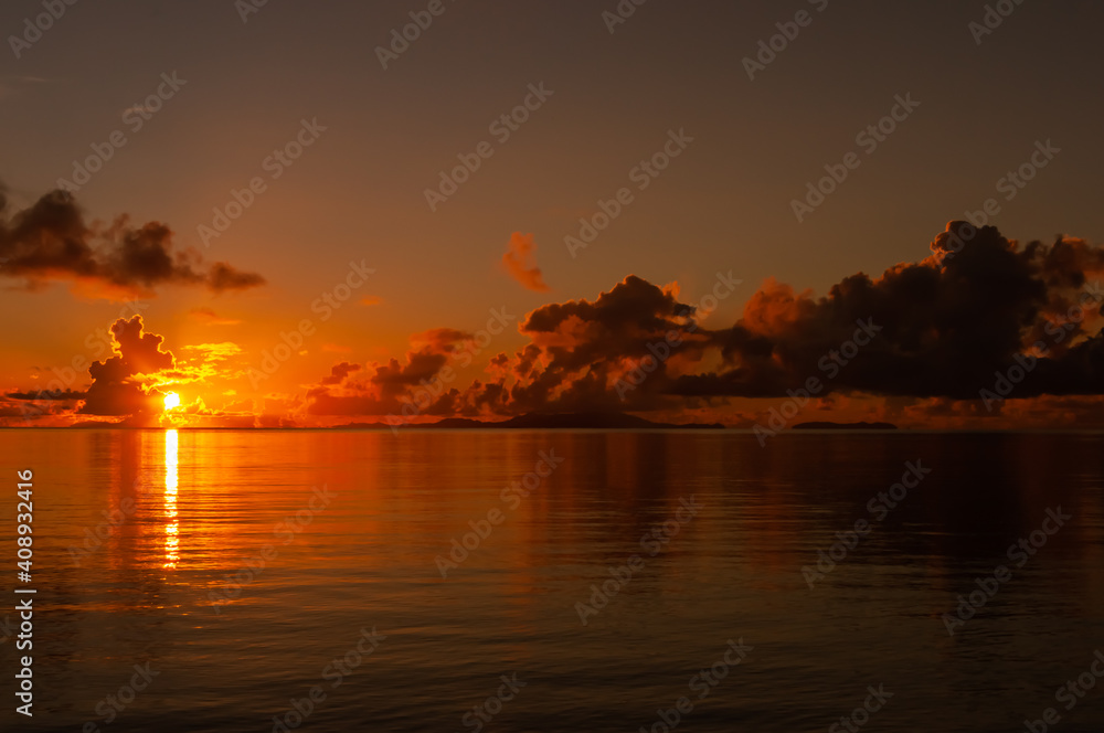 Dawn with the colors red, orange and yellow, and the sun rising on the horizon reflecting on the sea. Iriomote Island.