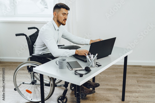 Fotobehang Positive disabled young man in wheelchair working in office