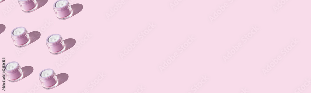 White antiaging face cream in pastel purple jar on pink background. Beauty skin care product pattern web banner