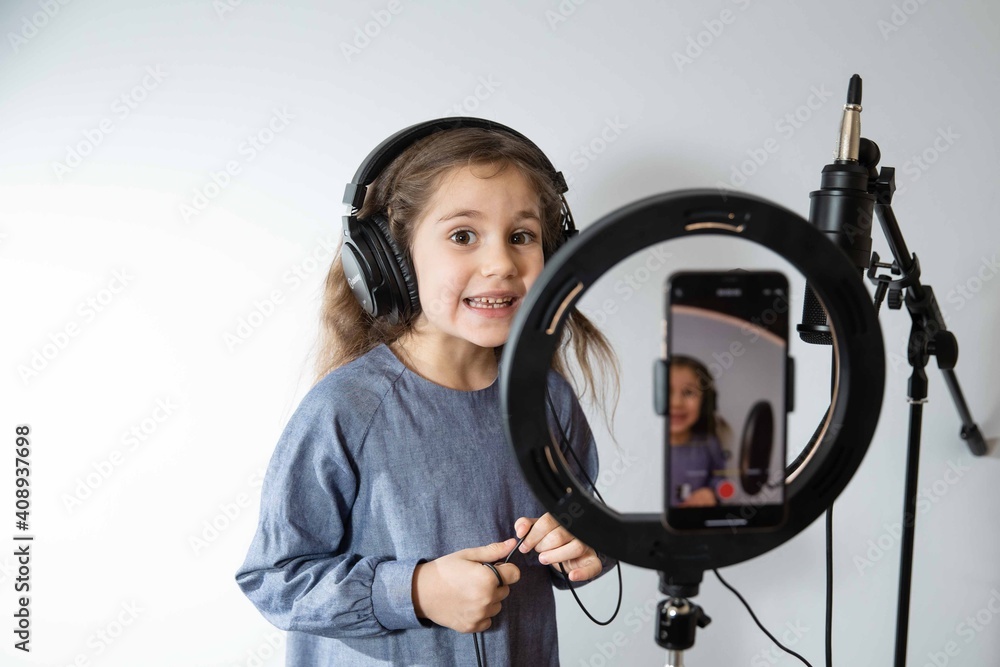 The girl blogger is broadcasting live. The girl is singing into the microphone. She is wearing headphones The girl blogger is broadcasting live. The girl is singing into the microphone. She is wearing headphones