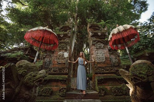 Young woman standing in temple gates at  temple in Bali, Indonesia. Beautiful nature place in Bali, travel concept photo