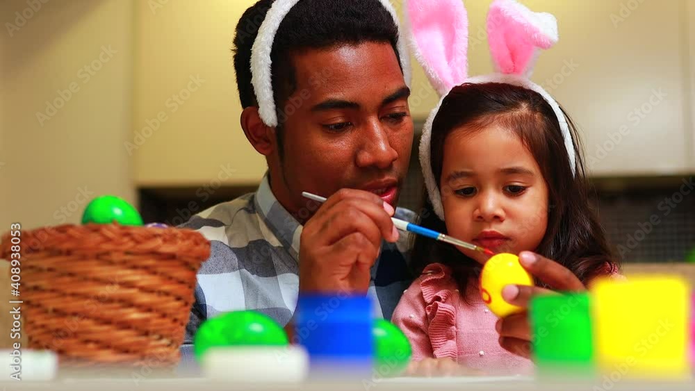 happy mixed race family celebrating Easter, painting eggs with brush smiling and laughing. happy mixed race family celebrating Easter, painting eggs with brush smiling and laughing.